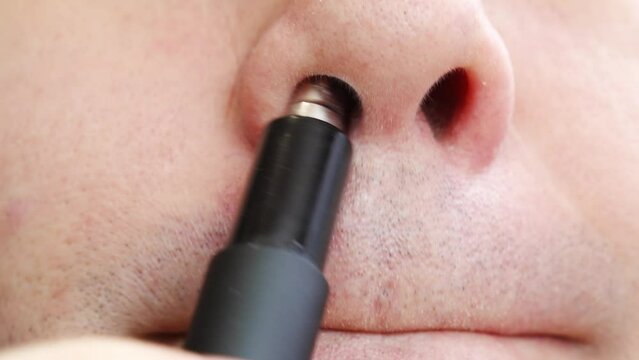 close-up. a man cuts his nose hair with a trimmer. the concept of personal hygiene and removal of excess hair.
