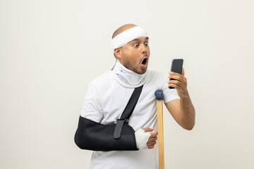 Happy young asian man broken arm holding smartphone. Asian man put on plaster bandage cast splint....