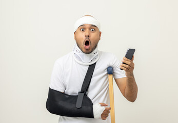 Happy young asian man broken arm holding smartphone. Asian man put on plaster bandage cast splint....