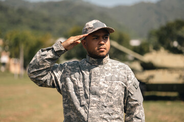 Asian man special forces soldier saluting standing against on the field Mission. Commander Army soldier military defender of the nation in uniform standing near battle tank while state of war.