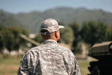 Asian man special forces soldier standing against on the field Mission. Commander Army soldier military defender of the nation in uniform standing near battle tank while state of war.