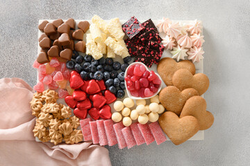 Charcuterie sweet board with chocolate, hearts,marmalade, different sweets, berries and candies on gray background. Top view. Appetizer and snacks dessert for romantic Valentines Day.