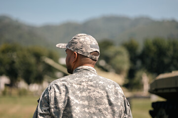 Asian man special forces soldier standing against on the field Mission. Commander Army soldier military defender of the nation in uniform standing near battle tank while state of war.