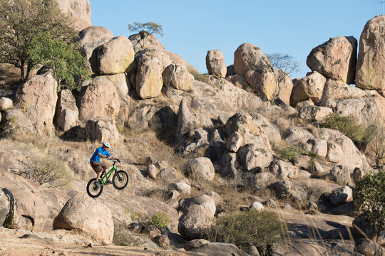 A man performs trial bike standing on a rock at El Diente, Jalisco, Mexico.