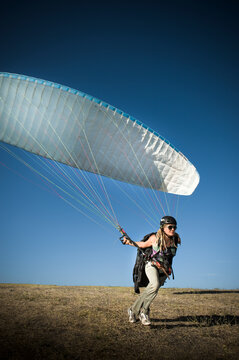 A young woman launching her paraglider in Santa Barbara, CA.