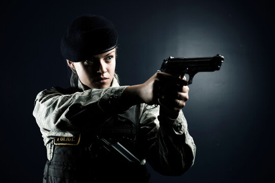 A Caucasian, female, Air Force Security Forces Airman in uniform poses with her M-9 pistol.