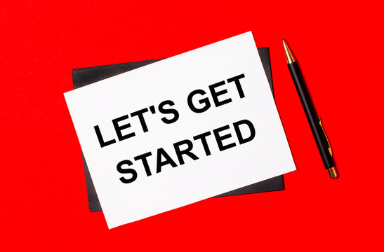 Black pen, envelope and white card with the text LET'S GET STARTED on a bright red background