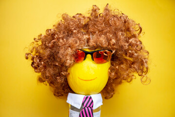 funny happy melon face in sunglasses and a wig on a yellow background, abstraction