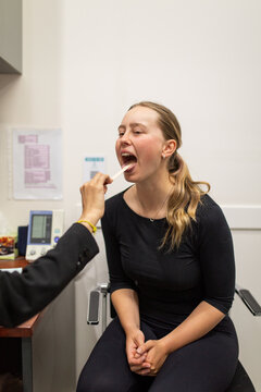 Woman's throat being checked in the clinic using a tongue depresser