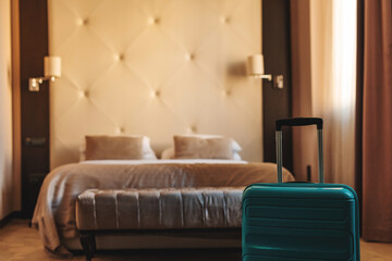 Blue travel suitcase in hotel apartment bedroom