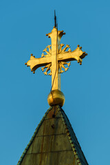 Gold colored Orthodox church cross against blue sky