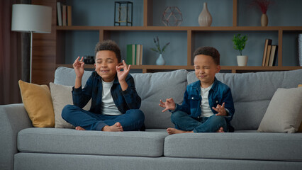 Two funny little African American ethnic children boys brothers siblings kids meditating together...