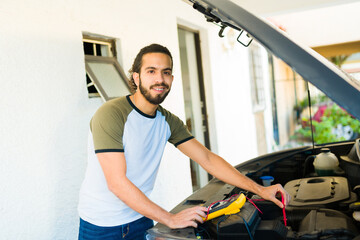 Fototapeta na wymiar Smiling man giving maintenance to the car battery