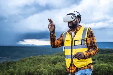 Tuinposter Portrait of engineer African American man working with VR headset in wind turbine farm. © Jirus