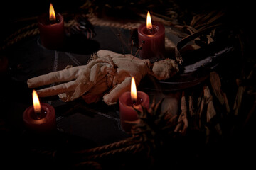 Voodoo doll, black candles, pentagram and old books on witch table. Occult, esoteric, divination...