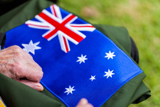 Australian flag patch sewn onto material with old mans hands resting on it
