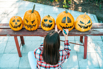 Preparing funny halloween pumpkins. A woman draws funny faces on pumpkins while sitting in a garden.
