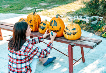 Preparing halloween pumpkins. A woman draws funny faces on pumpkins while sitting in a garden.