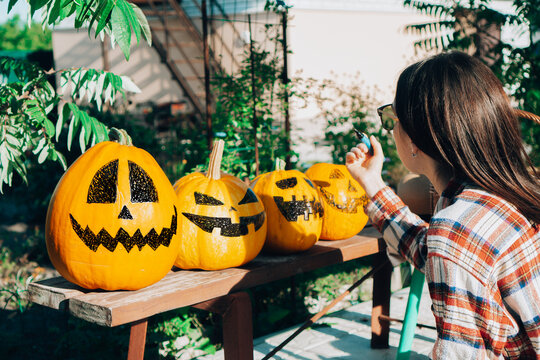 Preparing halloween pumpkin. A woman draws funny faces on pumpkins while sitting in a garden.