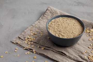 Organic White Oat Flour in a Bowl on a gray background, side view.