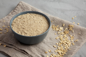 Organic White Oat Flour in a Bowl on a gray background, side view.