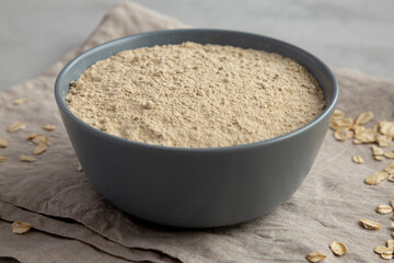 Organic White Oat Flour in a Bowl on a gray background, low angle view. Close-up.