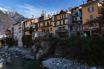 The riverside of the town of Chiavenna (Lombardy, Italy) with its historic houses and the mountains in the background, during a winter afternoon - January 2023.