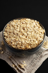 Wholegrain Oat Flakes in a Bowl on a black background, side view.