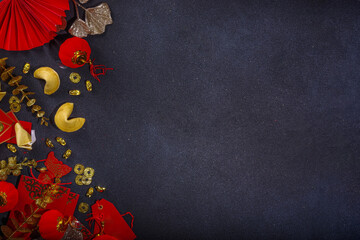 Chinese new year background, with festive red Chinese lanterns, paper fans and traditional New Year décor, stripes posters for wishes on black background top view copy space