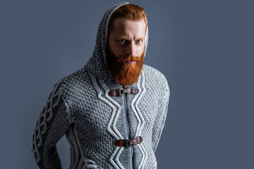 unshaven brutal man in warm knitwear at studio. brutal man in warm knitwear on background.