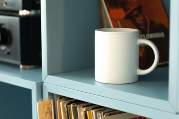 White mug on shelf with vinyls.