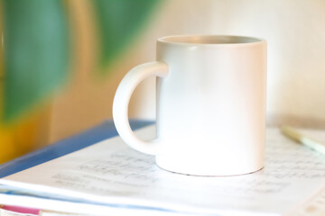 A white mug on a stack of papers