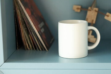 White mug on shelf with vinyls