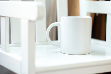 A white mug on a white chair - 562099119