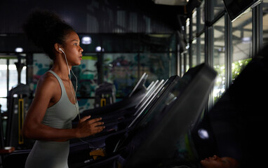Fototapeta na wymiar young sports woman working out with wired earbuds and running on treadmill in gym