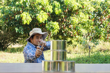 Asian man holds slingshot to play  shooting game, aim to shoot the  cans in forest. Concept,...