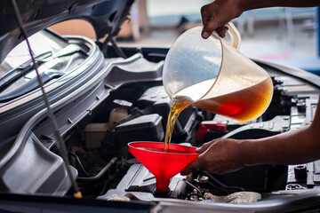 Car service, mechanic refill lubricant to car at the maintenance garage. Auto service, close up.  