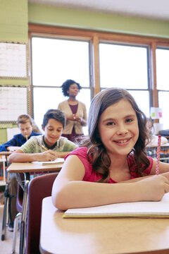 Happy, Students And Portrait Of Girl In Classroom With Notebook For Lesson Notes And Knowledge. School Kids, Learning And Development Of Middle School Children Writing In Academic Books.