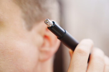 close-up. selective focus. a man cwith trimmers for cutting hair in the nose and ears. the concept of personal hygiene and removal of excess hair.