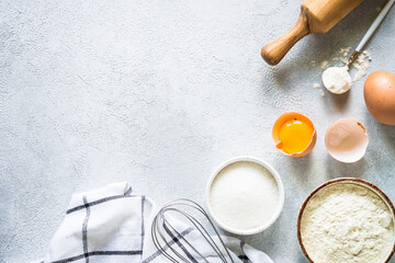 Baking background ingredients. Flour, sugar, eggs and others at light stone table. Top view with copy space.