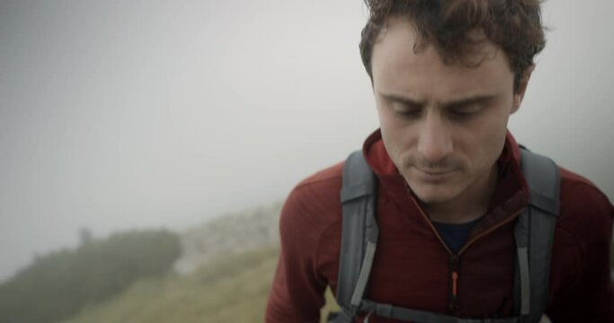 Close up of a hiker in red jacket, infront, climbin up a hill of mountain Stol. Windy conditions with low cloud cover.