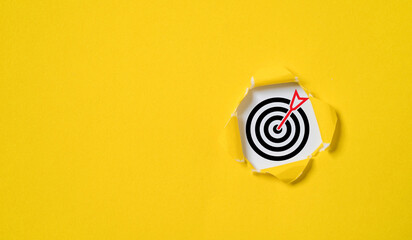 Dartboard with arrow inside of yellow punched paper for setup business objective target and goal concept. - obrazy, fototapety, plakaty
