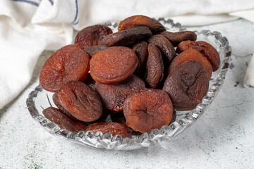 Dried apricots on stone background. Dark dried apricots in a glass bowl. Diet foods. close up