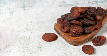 Dried apricots on stone background. Dark dried apricots on a wooden serving board. Diet foods. close up