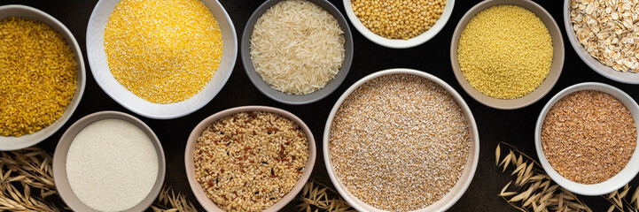 Various grain cereals in bowls banner, top view on a brown background with bowls of cereals and ears of oats