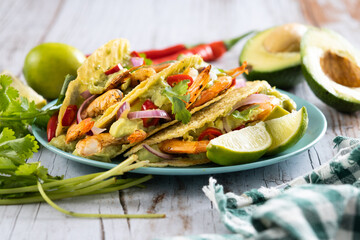 Mexican tacos with shrimp,guacamole and vegetables on wooden table