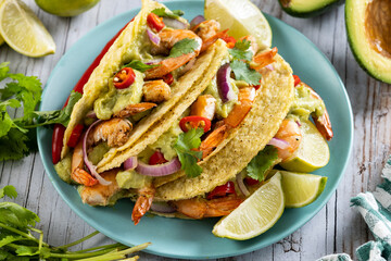 Mexican tacos with shrimp,guacamole and vegetables on wooden table