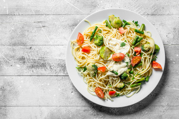 Pasta with vegetables and sauce on a plate.