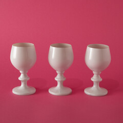 Three white wine glasses ready for a birthday party. The background is pink