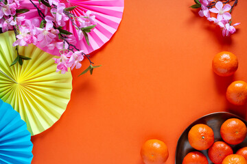 Chinese or lunar new year flat lay with paper decorations, mandarins and flowers on orange